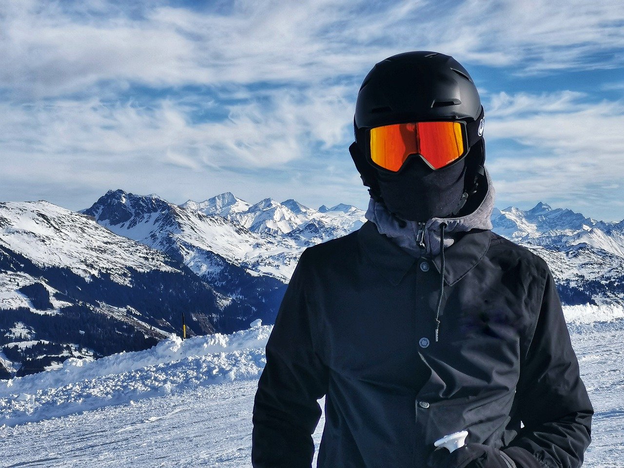 Skier wearing a helmet, goggles, neck gaiter, and layers of clothing